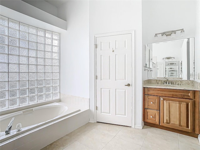 bathroom with tile patterned flooring, vanity, a wealth of natural light, and a tub to relax in