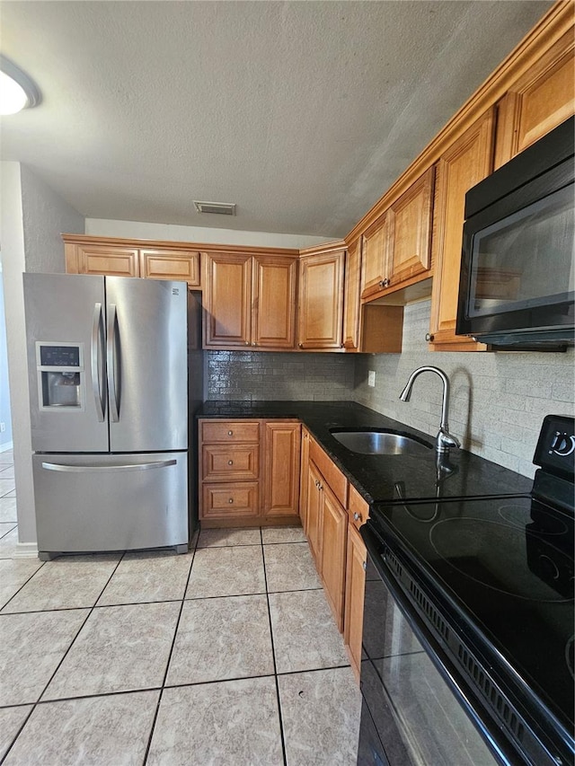 kitchen with sink, backsplash, a textured ceiling, light tile patterned floors, and black appliances