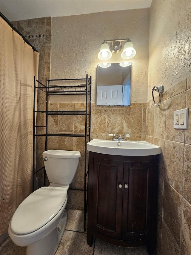 bathroom with a shower with curtain, vanity, toilet, and tile walls