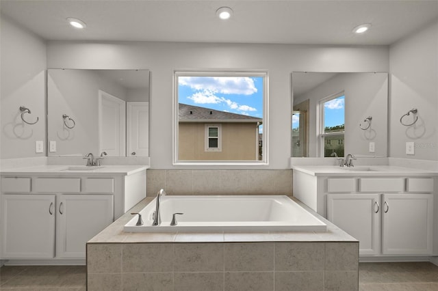 bathroom featuring a relaxing tiled tub and vanity