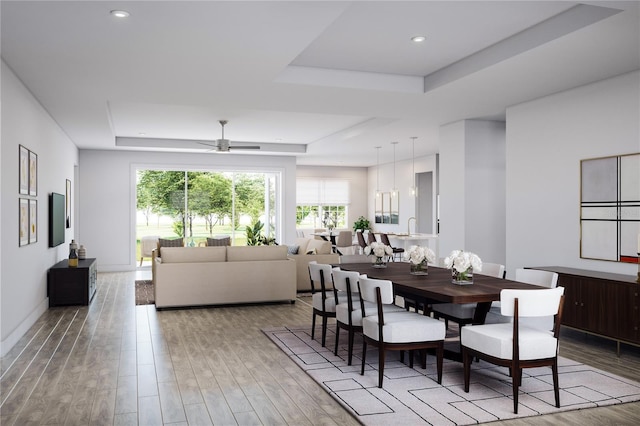 dining room featuring a raised ceiling, ceiling fan, sink, and light hardwood / wood-style floors