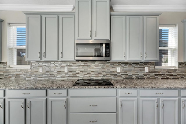 kitchen with plenty of natural light, black gas stovetop, light stone countertops, and decorative backsplash