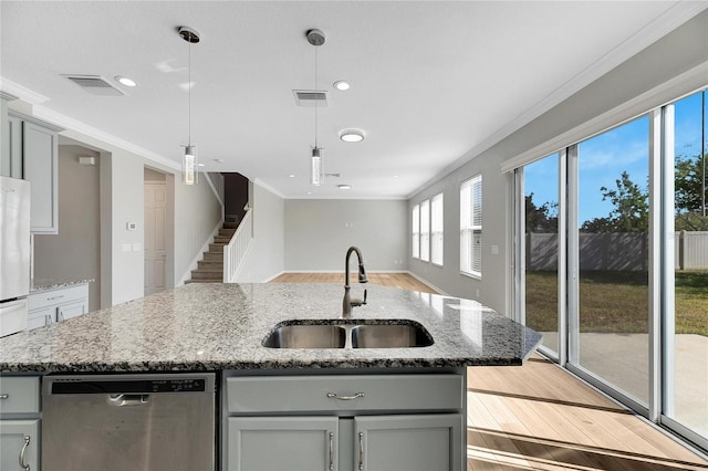 kitchen with light stone counters, dishwasher, a center island with sink, and sink