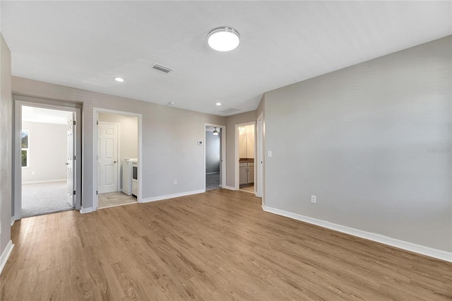 empty room with washing machine and dryer and light hardwood / wood-style flooring