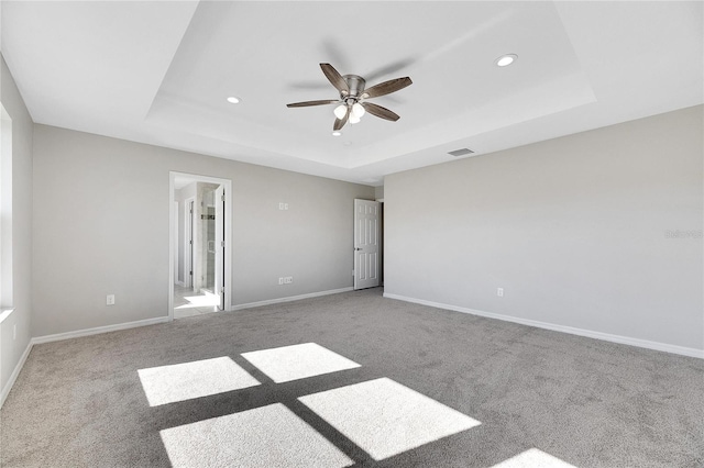 carpeted spare room featuring ceiling fan and a tray ceiling