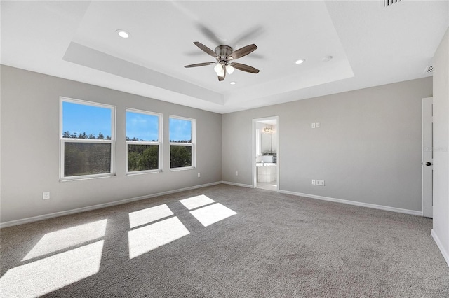 unfurnished room with a raised ceiling, ceiling fan, and carpet flooring