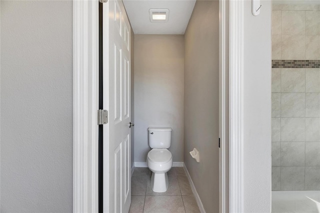 bathroom with tile patterned flooring, toilet, and tiled shower