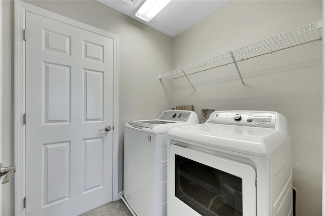 clothes washing area with a textured ceiling and washing machine and clothes dryer