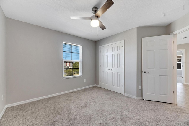 unfurnished bedroom with ceiling fan, a closet, light colored carpet, and a textured ceiling