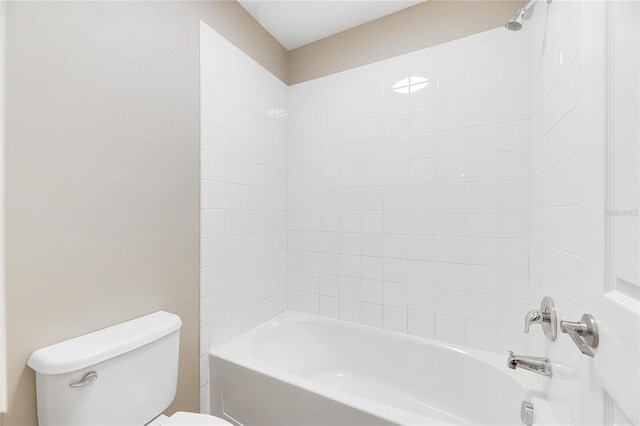 bathroom with toilet and tiled shower / bath