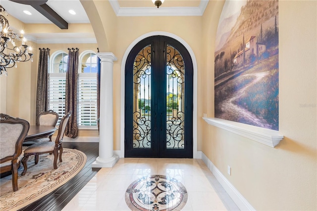 foyer with ornate columns, french doors, a chandelier, crown molding, and beam ceiling