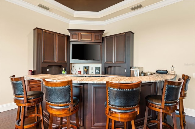 kitchen with dark hardwood / wood-style flooring, ornamental molding, kitchen peninsula, dark brown cabinets, and a breakfast bar area