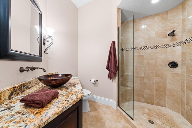 bathroom featuring toilet, vanity, and a tile shower