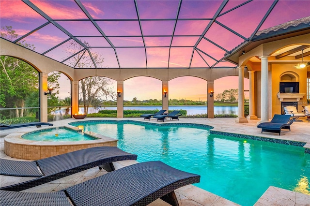 pool at dusk with exterior fireplace, a patio area, and an in ground hot tub