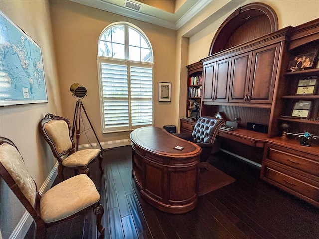 home office featuring dark wood-type flooring, crown molding, and built in desk