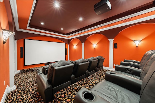 cinema featuring ornate columns, ornamental molding, carpet flooring, and a tray ceiling