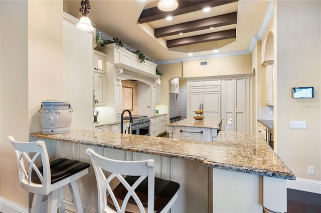 kitchen featuring kitchen peninsula, light stone countertops, a kitchen breakfast bar, and dark hardwood / wood-style floors