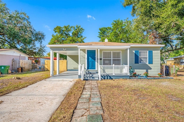 bungalow featuring covered porch, a carport, and a front yard