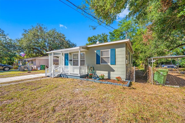 view of front of home with a carport, a porch, and a front lawn