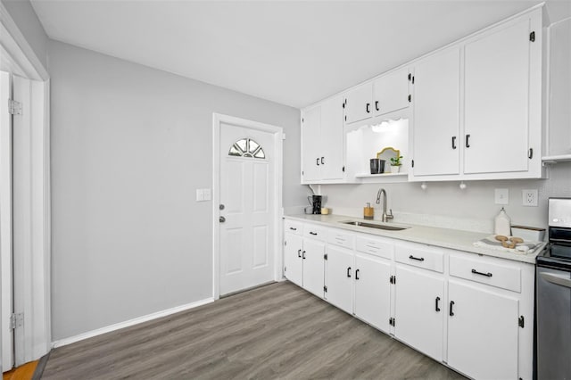 kitchen with white cabinets, light wood-type flooring, stainless steel range with electric cooktop, and sink