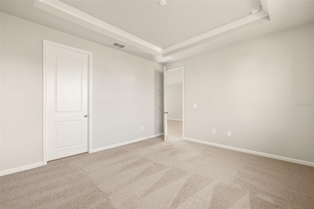 unfurnished room featuring light carpet and a tray ceiling