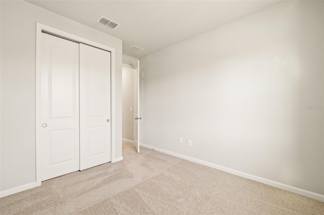 unfurnished bedroom with light colored carpet and a closet