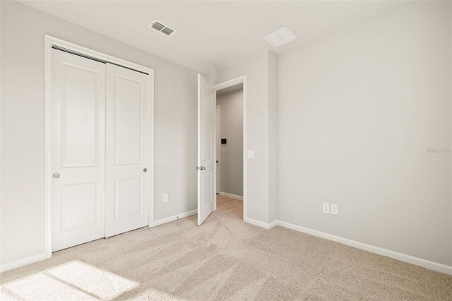 unfurnished bedroom featuring light colored carpet and a closet