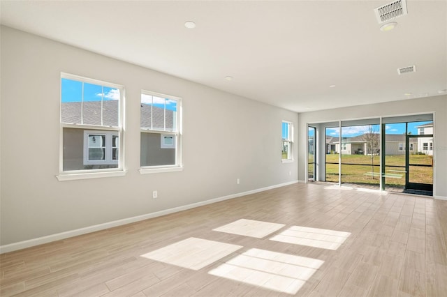 unfurnished room featuring a wealth of natural light and light hardwood / wood-style floors