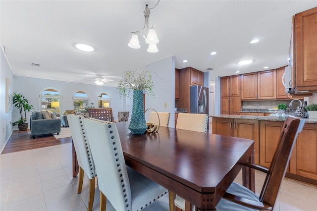 dining area featuring ceiling fan with notable chandelier, light hardwood / wood-style floors, and sink