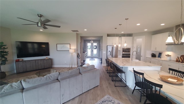 living room with ceiling fan, sink, and light hardwood / wood-style floors