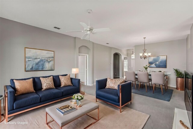 carpeted living room featuring ceiling fan with notable chandelier