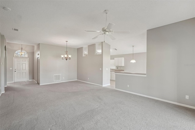 unfurnished living room with ceiling fan with notable chandelier, light colored carpet, and a textured ceiling