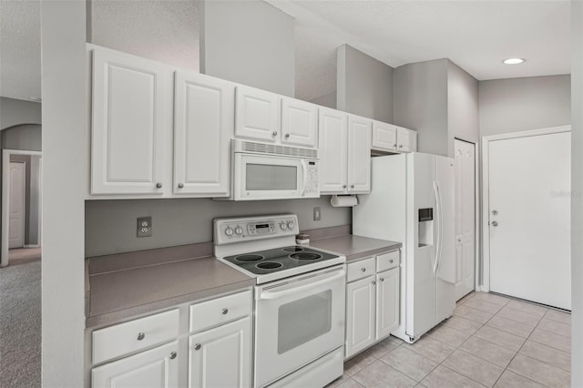 kitchen with white cabinets, light tile patterned flooring, white appliances, and a textured ceiling