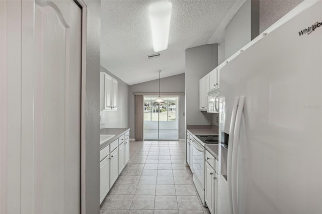 kitchen featuring a textured ceiling, white appliances, vaulted ceiling, light tile patterned floors, and white cabinetry