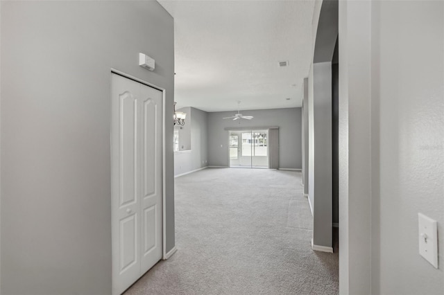 hall featuring light carpet and an inviting chandelier