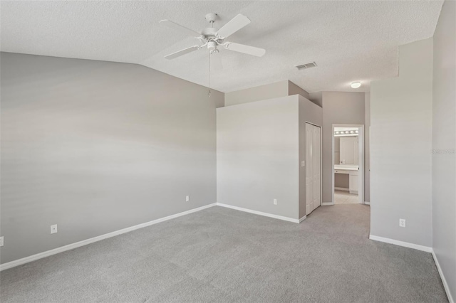 carpeted spare room featuring a textured ceiling, vaulted ceiling, and ceiling fan