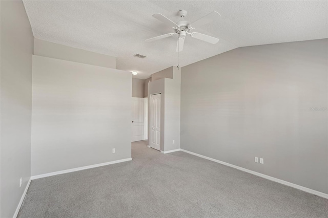 empty room with lofted ceiling, ceiling fan, light colored carpet, and a textured ceiling