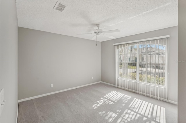 spare room with ceiling fan, a textured ceiling, and light carpet