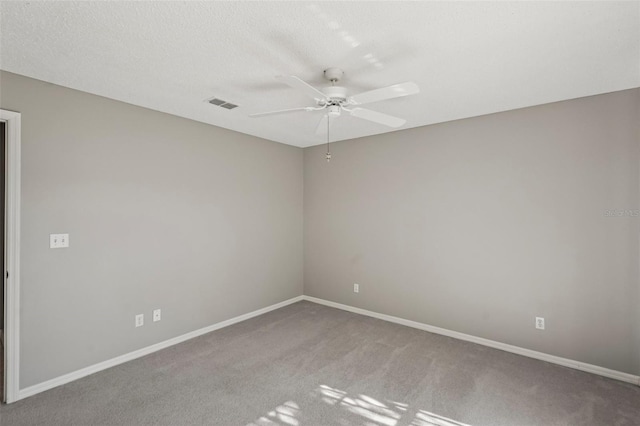 spare room featuring ceiling fan, light colored carpet, and a textured ceiling