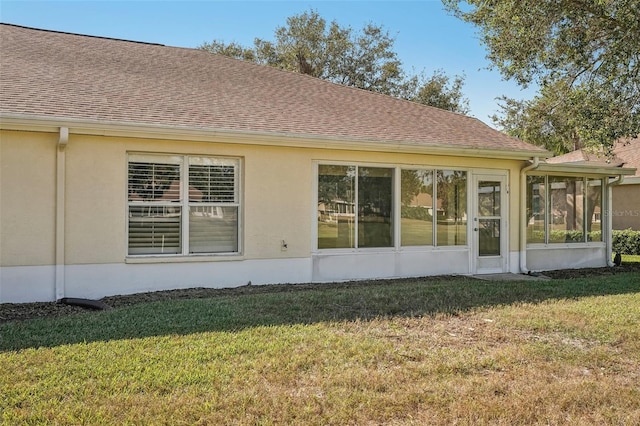 rear view of property with a lawn and a sunroom