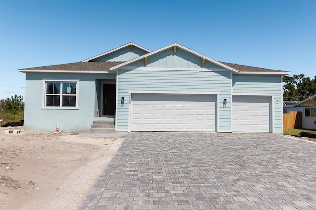 ranch-style house featuring a garage, decorative driveway, and board and batten siding