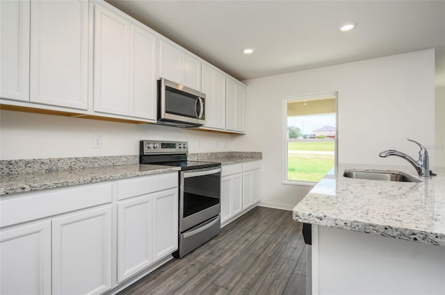 kitchen with light stone countertops, appliances with stainless steel finishes, sink, dark hardwood / wood-style floors, and white cabinetry