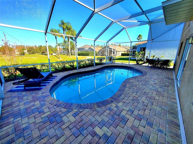 view of pool with a lawn, glass enclosure, and a patio area