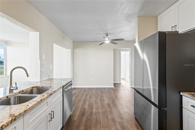 kitchen with light stone countertops, sink, dark hardwood / wood-style floors, white cabinets, and appliances with stainless steel finishes