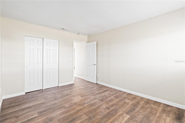 unfurnished bedroom featuring dark hardwood / wood-style flooring and a closet