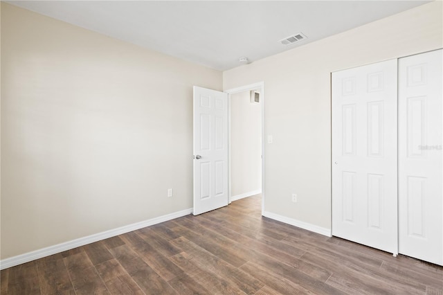 unfurnished bedroom featuring a closet and dark wood-type flooring