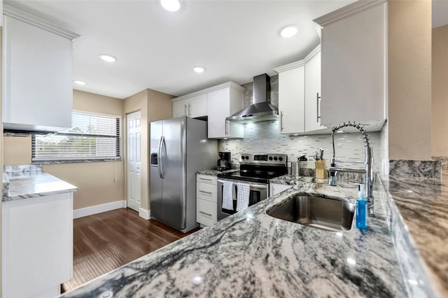 kitchen with light stone countertops, wall chimney exhaust hood, stainless steel appliances, sink, and white cabinets