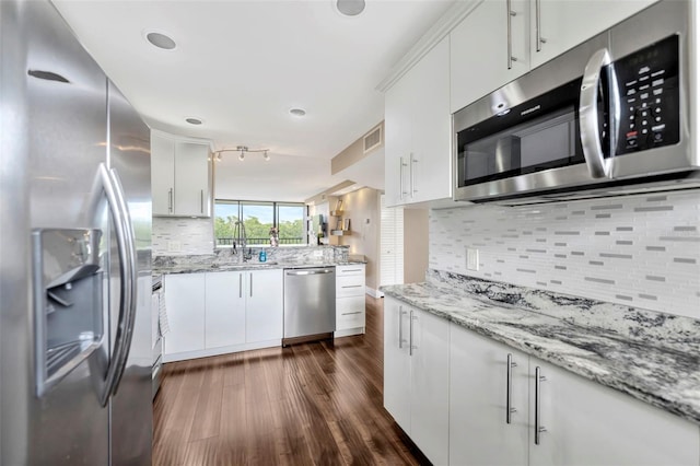 kitchen with tasteful backsplash, white cabinets, dark wood-type flooring, and appliances with stainless steel finishes