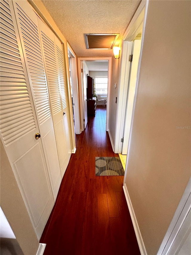 hallway featuring a textured ceiling and dark hardwood / wood-style flooring