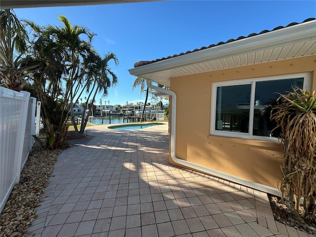 view of patio with a water view and a dock